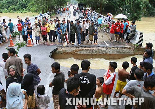 12月17日，在泰国的那拉提瓦府，当地村民观看被洪水冲垮的公路。新华社/法新