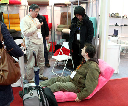 Un visiteur étranger essaie un canapé-lit présenté à la Foire de l'est de la Chine, organisée au Nouveau centre d'expositions internationales de Shanghai.
