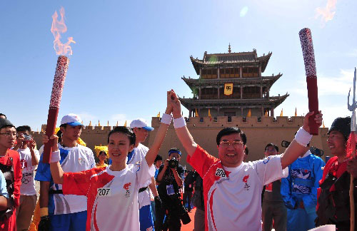 Torchbearers Zuo Xia (L) and Ma Guangming display the torches togethr during the 2008 Beijing Olympic Games torch relay in Jiayuguan, a city in northwest China's Gansu Province, on July 6, 2008.