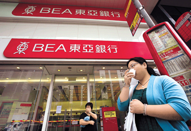  A customer stands at the font door of the Bank of East Asia in Hong Kong. [Shanghai Daily]