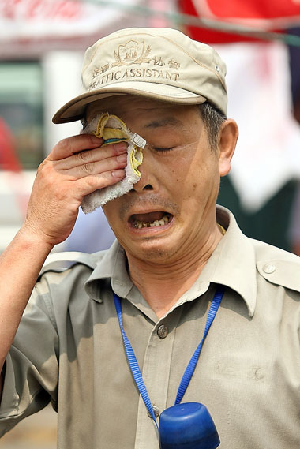 A traffic assistant wipes off sweat yesterday as the top temperature hit 36 degrees Celsius.