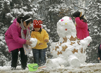 A young girl gets some help building a snowman at a park in Wuhan, capital of central China's Hubei Province. Wuhan's education authority ordered the city's schools and kindergartens to suspend classes yesterday because of the rare heavy snow.