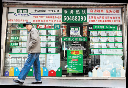 A pedestrian walks past a real estate brokerage in the city's Pudong New Area. [Shanghai]