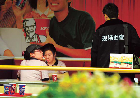 A police officer questions employees at a KFC outlet hit by tragedy on Monday.