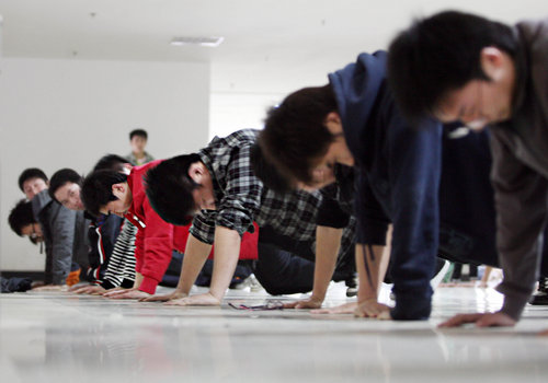 Students from Wuhan Institute of Shipbuilding Technology is doing push-up at a job fair held by Foxconn quasi-Precision Mold Co Ltd, in Wuhan, Hubei province, on March 23, 2010. Boys who complete 20 push-ups are considered qualified, 30 excellence, and 10 for girls. 