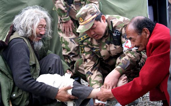 A medical worker of the Chinese public security frontier defense troop helps Zhaxi Deleg of the Tibetan ethnic group injured in the earthquake to bandage up his leg in Gyegu Town of Yushu County, northwest China's Qinghai Province, April 20, 2010. The quake-jolted area in Qinghai was attacked by a hailstorm Tuesday, which hampered the disaster relief efforts. 