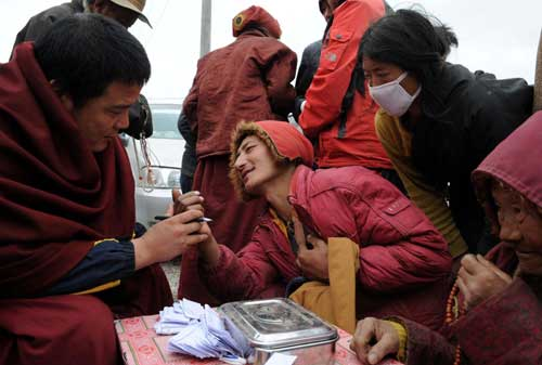 A Tibetan doctor (L) examines a quake victim at a temporary shelter in Yushu prefecture of Qinghai province, April 20, 2010. A medical group with 27 doctors from the Jigme Tibetan hospital in Xining rushed to quake-hit Yushu and provided medical service for quake victims free of charge. Their traditional Tibetan treatment is well received among local residents. 