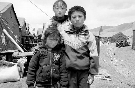 Tsering Lodin (right), a 10-year-old Tibetan boy who helped three classmates escape from the Yushu earthquake, stands with his sisters in a quake tent area in Yushu.