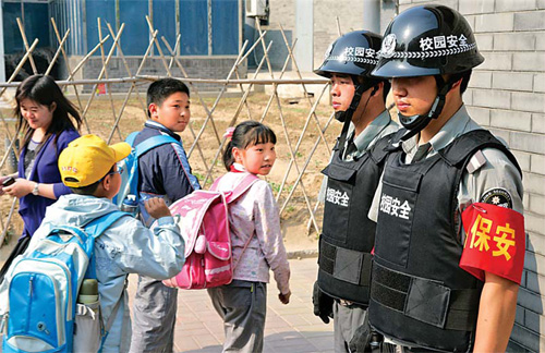 Students at Beijing No 1 Experiment Primary School are escorted by security guards on Thursday.