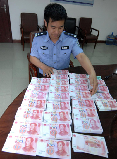A policeman shows the fake bills seized in an RMB counterfeit case in Xi'an, Shaanxi province, on May 25, 2010. The suspect, surnamed Zhang, used a color inkjet printer to make 250,000 yuan in fake money ($36,616). 