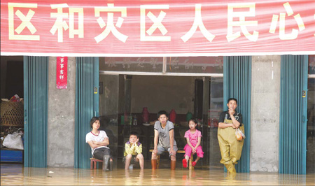 Residents in Changkai, eastern Jiangxi province, wait for the floodwaters to disappear. The town was soaked for about a week after the nearby Fuhe River burst its banks on June 21. 