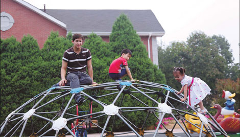 David and Cici Li play with their American au pair, Javier Cantu, at the playground in their neighborhood. Cantu came from Texas to spend the summer teaching the children English and learning about Chinese culture. Christie Lee / For China Daily     