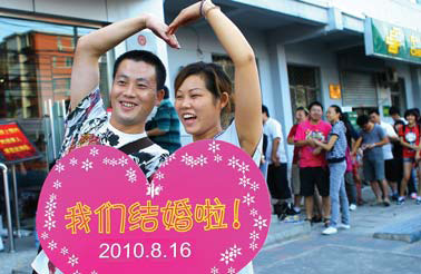 Zhang Junhua (left) and Huang Shaohua pose for a photograph, holding a heart-shape placard that reads 'we're married!' after receiving their marriage certificate at Chaoyang district marriage registry office in Beijing on Monday. 