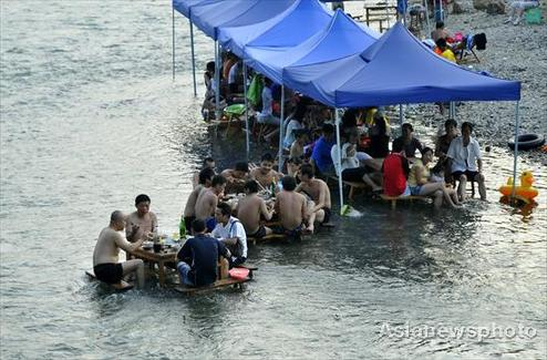 People have dinner in a village river in Kaili, Southwest China's Guizhou province on August 9, 2010. The continuing high temperatures have driven thousands of city dwellers to the village river every day. They swim, play cards and have dinner in the river.