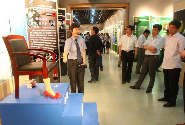 A guide points to a chair propped up by depictions of common methods of bribery: Sex, wining and dining, and cash. The chair was on display at an anti-corruption exhibition in Kaifeng, Henan province, in this file photo. [Bian Xuan / For China Daily]