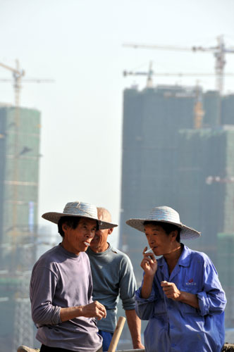Three migrant workers smoke at the construction site of a low-rent housing project in Chongqing on Oct 31. [Provided to China Daily] 