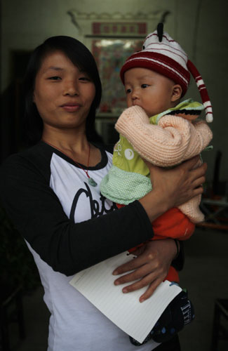  Zhou Qiuhua, 24, holding her son, plans to get back to work in cities when the boy is 1 year old.
