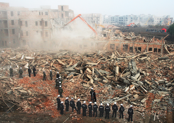  Police and urban management officers guard a massive demolition site in Wuhan, Hubei province, on Tuesday, when the local government sent more than 2,000 officers and construction workers to demolish unauthorized construction in Houhu village in the city. It was the largest demolishing action of its kind in the city's history.[China Daily]