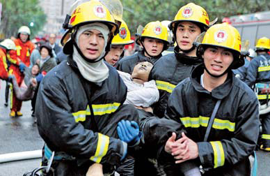 Fire rescue workers carry a survivor from the blaze in a residential tower block in Shanghai's Jing'an district. 