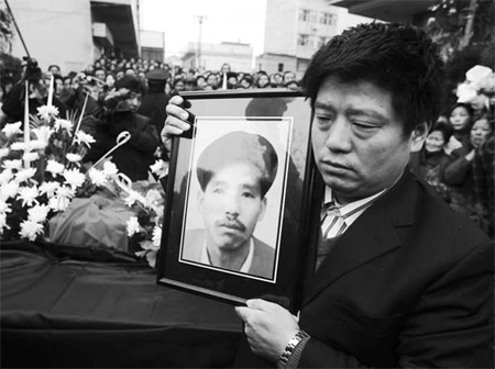 Sun Donglin holds a portrait of his brother Sun Shuilin at his funeral in Wuhan, capital of Hubei province, on March 2. His brother died in a traffic accident while rushing to pay wages to his workers. 