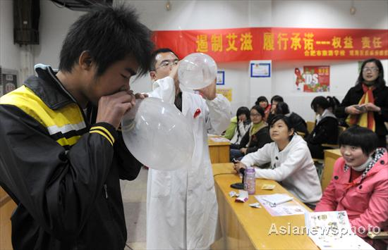 A staff member from the disease prevention and control bureau of Yaohai District plays games with students in Hefei, Anhui province on Nov 29, 2010. As World AIDS Day comes on Dec 1, staff from the disease prevention and control bureau go to schools to raise awareness about preventing AIDS/HIV infections through games and presentations.