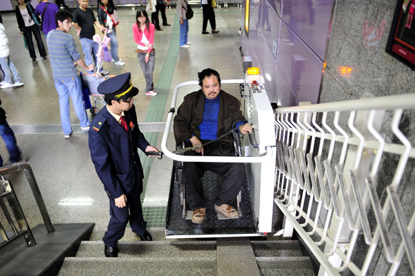 A subway worker in Guangzhou, capital of Guangdong province, operates an electrical stairlift to assist a passenger with leg problems on Dec 2. [Liang Xu / Xinhua] 