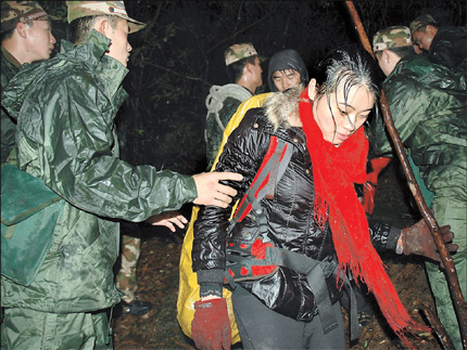 Armed Police officers guide one member of a group, which included students from Shanghai's Fudan University, to safety yesterday after they got lost in the Yellow Mountain scenic area in Anhui Province. All 18 members of the group were safe after about 11 hours of rescue efforts involving around 200 people but one policeman died as he was escorting them from the mountain.