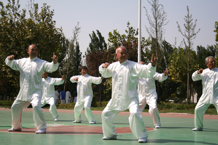 A group of elderly people practice qigong at a local park.