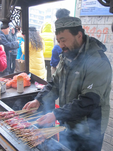 Alimjan Halik roasts kebabs in Bijie, Guizhou province, on Jan 21. 
