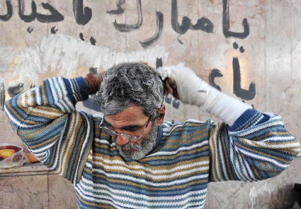 A demonstrator combs hair after waking up at Tahrir Square in Cairo, capital of Egypt, Feb. 8, 2011. Demonstrations demanding resign of President Hosni Mubarak continued, though the new government approved 15-percent pay raise for government employees. 