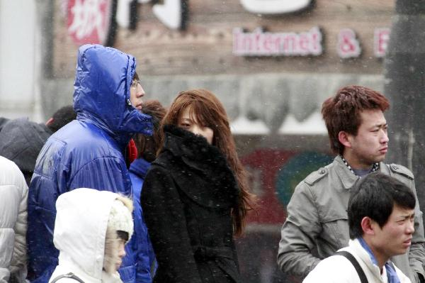 People in thick clothes are seen on the street in Dalian, northeast China's Liaoning Province, Feb. 8, 2011. Many places in China witnessed temperature drop due to strong cold air in recent days. 