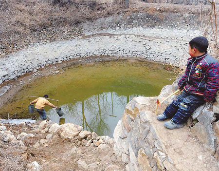 A villager collects water from a pond that is drying up in Jiangling village in Songxian county, Central China's Henan province, on Monday. A severe drought has made it difficult for 3,600 people and 970 cattle in the county to find adequate drinking water.