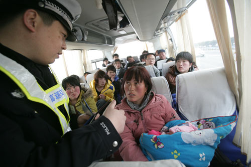 A traffic police officer in Hebi, Henan province, checks passengers on a bus while looking for suspects involved in the abduction of children. [Photo/China Daily] 