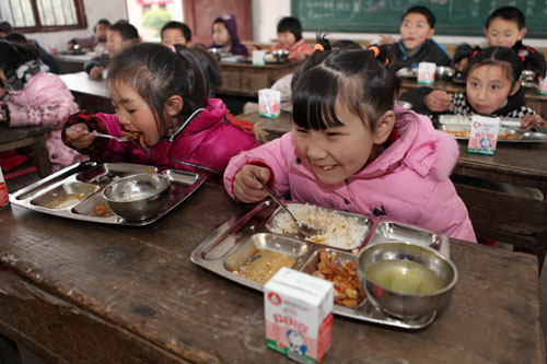 Pupils at a primary school in Chongqing's Dazu county eat free lunches on Feb 16. To better ensure the nutrition of local children, the county launched a 10-million yuan program to offer free lunches to 6,000 children from poverty-stricken families or those left behind while their parents work in cities. 