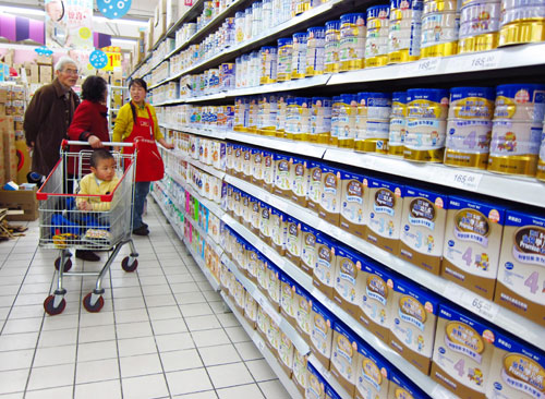 A saleswoman (right) shows dairy products to consumers in a supermarket in Beijing on Monday.