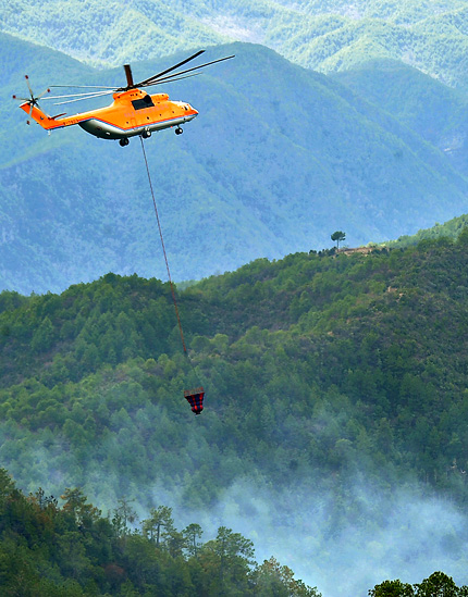 A Mi-26 helicopter (above) joins the battle to control a mountain fire in Jianchuan County, Yunnan Province, yesterday. Authorities have mobilized two helicopters and more than 1,000 people to fight the inferno. The fire has killed nine firemen and volunteers and left another seven people injured.  