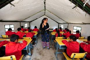 Pai Mudong teaches a class as students returned to school yesterday, four days after an earthquake struck in Yingjiang County, Yunnan Province. 