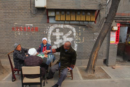 Four local residents play mahjong in front of a house at Panjia Hutong, 100 meters away from Liang Qichao's yard. The houses have been scheduled for imminent demolition.