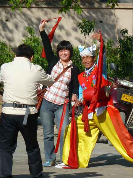 A tourist takes pictures with a folk dancer in Yan'an, Shaanxi Province, on May 14. A major power base for the Communist Party of China in 1935-49, Yan'an is a pilgrimage destination for Party members from across the country.