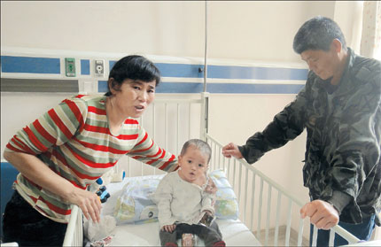 Foster parents Qian Fenglan (left) and Cui Kaichun with 20-month-old Chenxi at a local hospital. The couple have sold most of their property to fund the infant's heart surgery.