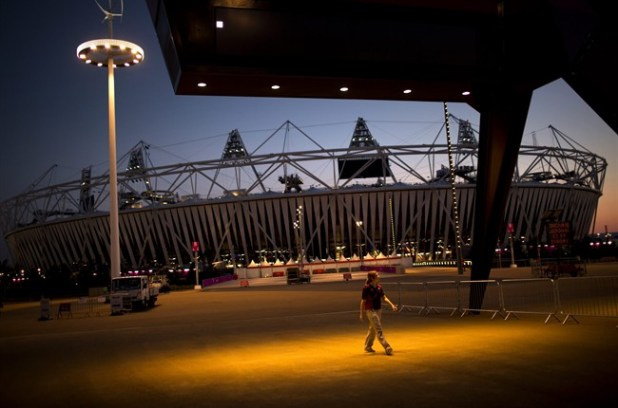 A volunteer walks past the Olympic Stadium at the 2012 Summer Olympics, Sunday, July 22, 2012, in London.