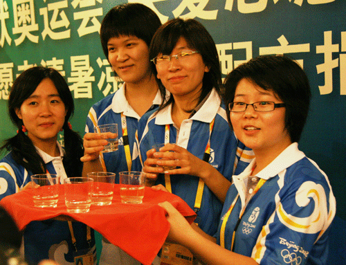 Volunteers for the Beijing Olympics and Paralympics taste tea at a donation ceremony held by the Chinese Traditional Medicine Association in Beijing on July 17. 