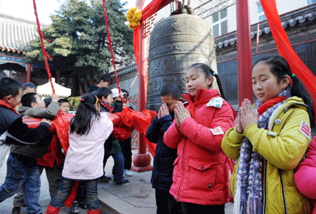 Pupils of Chaocheng Road Primary School ring a bell to pray for blessings in the upcoming new year in Qingdao, east China's Shandong Province, on Dec. 30, 3008. As the New Year draws near, lots of residents here come to ring the bell in Folklore Museum of Qingdao, to wish a peaceful and happy new year. (Xinhua/Li Ziheng)