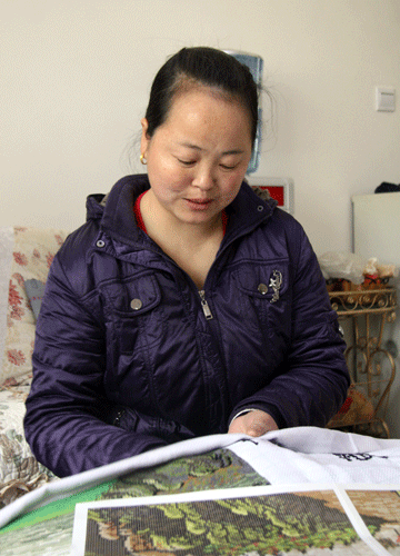 Xu works on embroidery to present to the government of Dongguan City which helped rebuild her village. 
