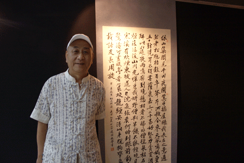 Zhao Wulong, 59, a famous calligrapher from Beijing poses with his work at the Beijing-Taipei Painting Exhibition which kicked off at the China Millennium Monument in Beijing, June 24th, 2010.