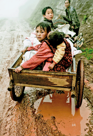 Younger brother on her back, Qubiag takes the ox cart home. Photo: Wu Chuanming 