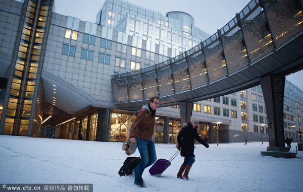 People walk in the snow in front of the European Parliament headquarters in Brussels, 03 February 2012. 