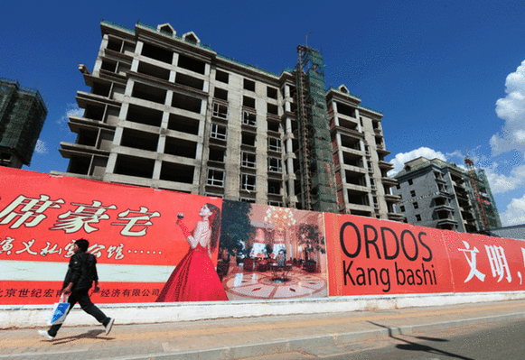 A pedestrian walks by a real estate project site. [File photo]