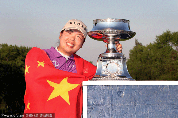 Shanshan Feng of China wraps herself in the flag of China and poses with the championship trophy after winning the Wegmans LPGA Championship at Locust Hill Country Club on June 10, 2012 in Pittsford, New York.