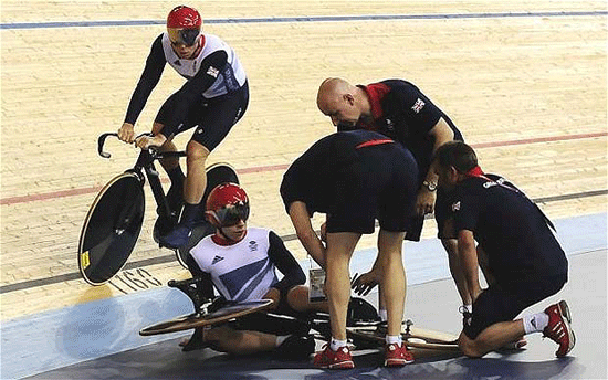 Hoy rides past as Team GB staff attend to Philip Hindes' bike after a crash on the first bend in the team sprint final